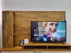 a flat screen tv sitting on a wooden shelf at TH Flats GV in Governador Valadares