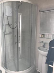 La salle de bains est pourvue d'une douche avec une porte en verre. dans l'établissement The St. Leonards Guest House, à Shanklin