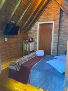 sypialnia z dużym łóżkiem w drewnianym pokoju w obiekcie Chalés Snow w mieście Urubici