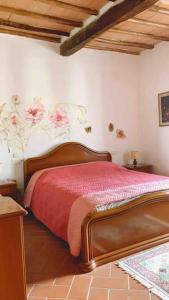 a bedroom with a bed with red sheets and flowers on the wall at Casa nella roccia in Roccastrada