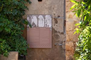 a plaque on the side of a wall with plants at San Salvatore Monastery in Chania