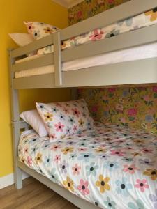 a bedroom with two bunk beds with a flowery bed at Bryn Castell, Conwy in Conwy