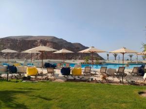 un grupo de sillas y sombrillas junto a una piscina en Beautiful chalet in Il Monte Galala المونت جلالة ch15-01-01, en Ain Sokhna