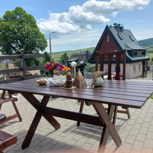 einen Picknicktisch aus Holz auf einer Terrasse mit einem Haus in der Unterkunft Apartments - Lehmanns Ferienwohnungen in Kurort Oberwiesenthal
