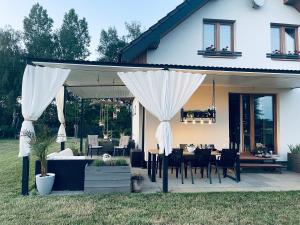 un patio con mesa y cortinas blancas en Żuławski Chillout 
