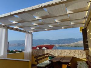 a pergola on a balcony with a table and a view of the water at Family apartments Grguric in Pag