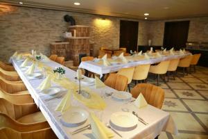 a long table in a room with white tables and chairs at Villa Florencia in Bardejov +32 photos