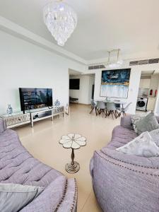 ein Wohnzimmer mit einem lila Sofa und einem TV in der Unterkunft Luxurious 2 bedroom Beachfront Apartment - direct seaview in Ras al Khaimah