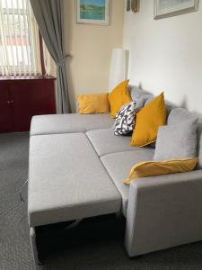 um sofá cinzento com almofadas amarelas numa sala de estar em Gables Seaview 4 school Str Largs top floor em Largs