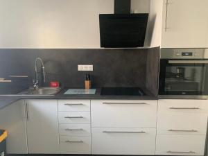 uma cozinha com armários brancos, um lavatório e um micro-ondas em Chez Georges et Rosa em Ingersheim