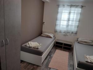 mały pokój z 2 łóżkami i oknem w obiekcie Apartmani Verica w mieście Karlobag