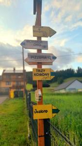 a wooden sign with arrows pointing in different directions at Spiska Dolina in Łapsze Niżne