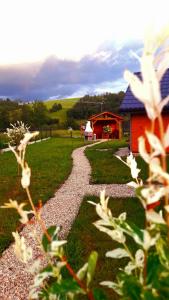 a gravel path leading to a red building with a house at Spiska Dolina in Łapsze Niżne