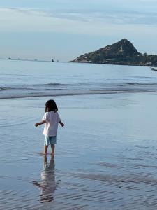a little girl standing in the water on a beach at ลา กาซิตา หัวหิน by สามใบเถา in Hua Hin