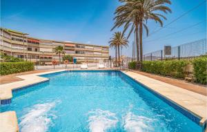 a swimming pool in front of a building with palm trees at Beautiful Apartment In Cabo De Gata With 2 Bedrooms And Outdoor Swimming Pool in El Cabo de Gata