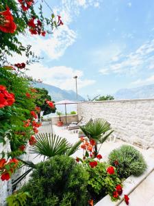 a patio with red flowers and plants at Three Dots by Todorovic Family in Kotor