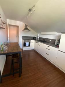 a kitchen with white cabinets and a wooden table at Ferienwohnung Baumgartner Chiemseeliebe 2OG in Breitbrunn am Chiemsee