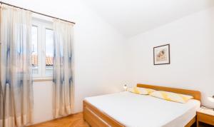 Apartments Mrak في بونات: غرفة نوم بيضاء بها سرير ونافذة