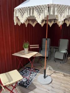 a table with an umbrella next to two chairs at Attefallshus Alingsås / Dammen. in Alingsås