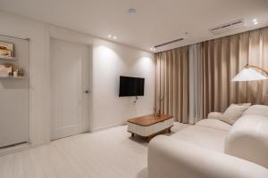 a living room with two white couches and a tv at Koon Terrace Stay in Seoul