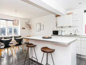 una cocina con armarios blancos y taburetes de bar en Holiday home Thyborøn III, en Thyborøn