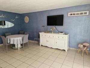 Le Refuge Du Plessie 4 Étoiles في بلوا: غرفة طعام مع طاولة وتلفزيون على جدار أزرق