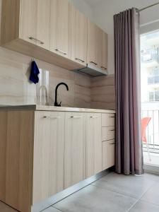 a kitchen with wooden cabinets and a sink and a window at Vila Manuel in Shëngjin