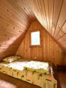 a bed in a log cabin with a window at Apartman Kurjak in Šavnik
