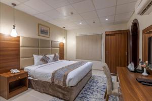 Una habitación de hotel con una cama y un escritorio y un escritorio. en Rose ALMedina روز المدينة, en Medina
