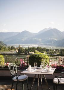 a table and chairs on a balcony with mountains in the background at Hotel Rosengarten (Schenna Resort) in Schenna