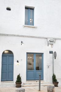 un edificio bianco con una porta blu e due finestre di B&B Visìta_experience a Torre Santa Susanna