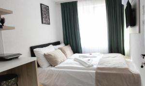 Schlafzimmer mit einem Bett mit weißer Bettwäsche und einem Fenster in der Unterkunft Apartments HAN 2 Sarajevo in Sarajevo