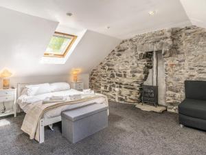 - une chambre avec un lit et un mur en pierre dans l'établissement The Forge, à Llanfair Clydogau