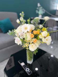 eine Vase Blumen auf einem Tisch mit Fernbedienung in der Unterkunft Su Apartment in Da Lat