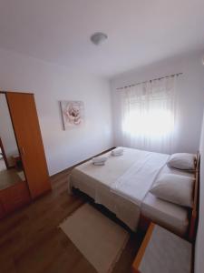 a white bedroom with a bed and a window at MaroVito in Supetarska Draga