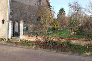 una valla frente a un edificio con una puerta en Maison de campagne à 2h de Paris, en Andryes