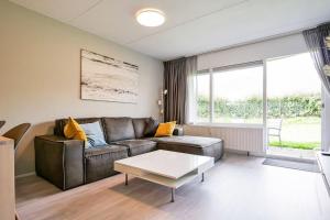 een woonkamer met een leren bank en een tafel bij Beach Appartement 10 - Aan de duinen, Callantsoog aan Zee in Callantsoog +25 foto's