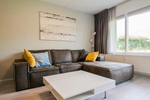 een woonkamer met een bruine leren bank en een tafel bij Beach Appartement 10 - Aan de duinen, Callantsoog aan Zee in Callantsoog