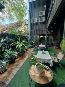 um pátio exterior com mesas, cadeiras e plantas em Rangyen Homestay Cha-Am รังเย็น em Cha Am