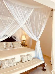 a bedroom with two beds with white curtains at Simba Wa Kale Suites & Beach in Watamu