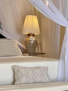 a bedroom with a bed with a lamp on a table at Simba Wa Kale Suites & Beach in Watamu