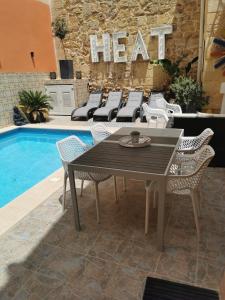 una mesa y sillas junto a una piscina en Large Bedroom in Boutique Style Farmhouse B&B with Pool, en Il-Pergla
