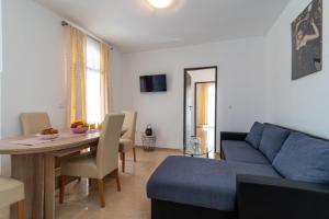 ein Wohnzimmer mit einem blauen Sofa und einem Tisch in der Unterkunft Beachfront apartments Jurica with balcony in Trogir