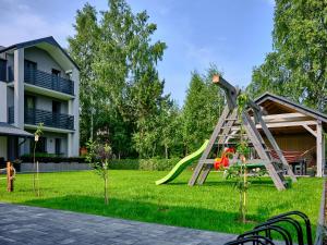 a playground in a yard with a slide at Slow Łeba Relaksowa - Apartamenty z aneksami kuchennymi in Łeba