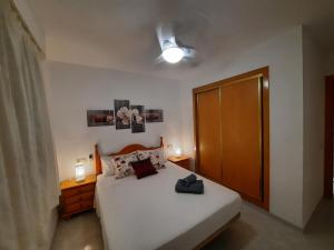 1 dormitorio con cama blanca y puerta de madera en Alcossebre RESIDENCIAL ALANDALUS 5002 en Alcossebre