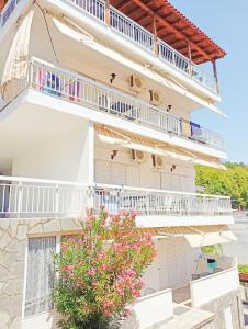 een groot wit gebouw met balkons en een boom bij House Charistos in Neos Marmaras