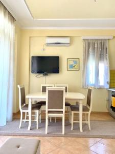 a dining room with a table and chairs and a tv at Four Seasons Beach Apartment Golem in Golem +28 photos