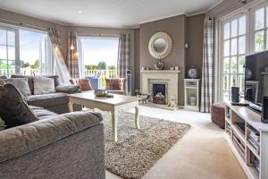 Una sala de estar con un sofá y una chimenea. en Windrush Lake 80 & 81, Waterlow Lodge P, en South Cerney