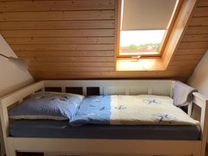 Bett in einem kleinen Zimmer mit Fenster in der Unterkunft HAusZeit Kapitänshaus Friedrichsschleuse in Carolinensiel