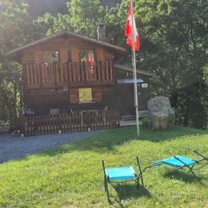 a cabin with a flag and two chairs in the grass at Le Passage in Salvan